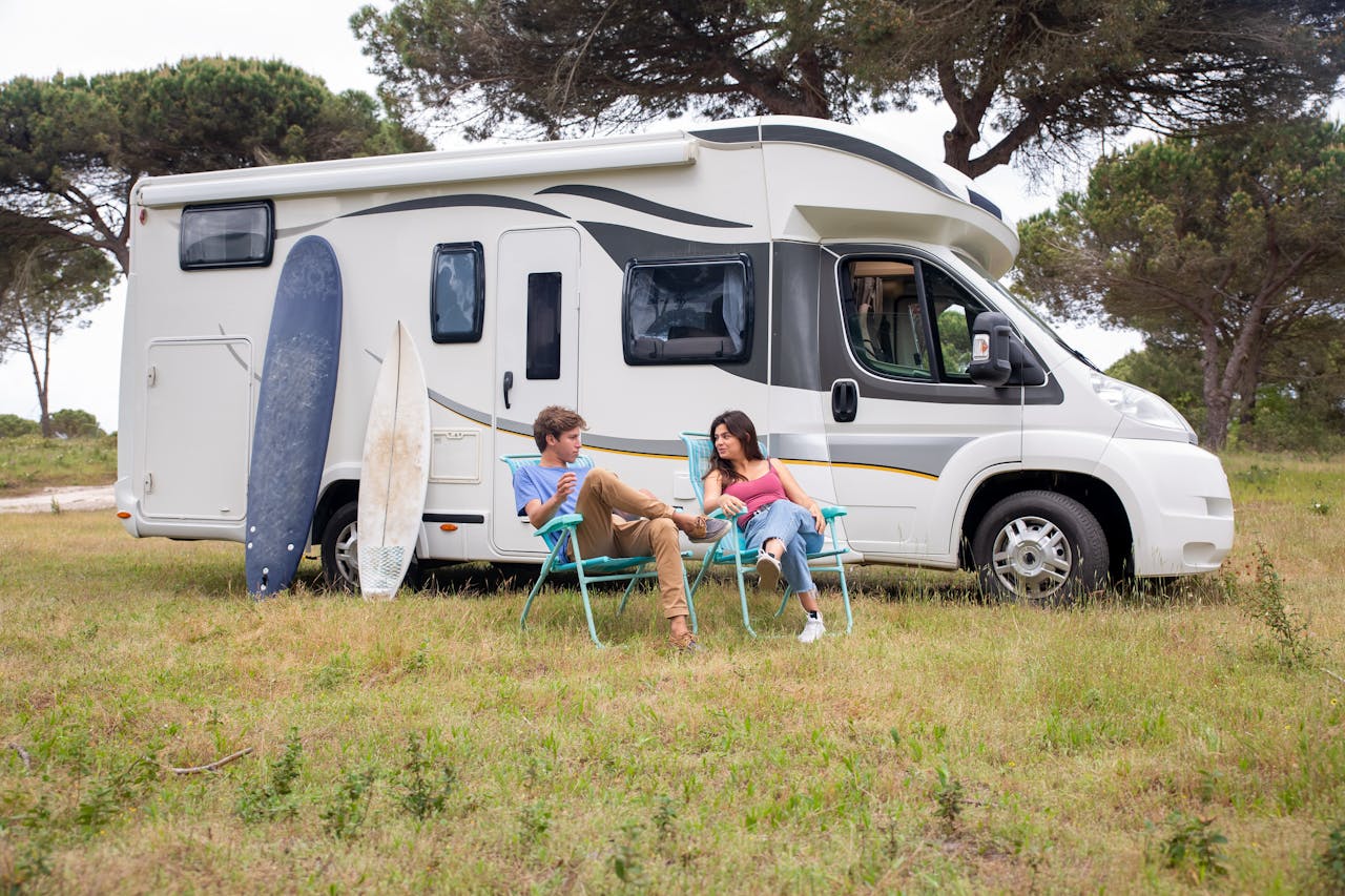 about-02 A young couple enjoys leisure time by their campervan in a sunny outdoor setting.